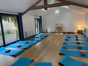 Salle des cours de Kundalini Yoga au centre Natur'Ô Zen, avec une disposition des tapis de pratique au sol autour de la pièce